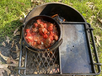 A pot of chilli on a camping cook pot, over a fire